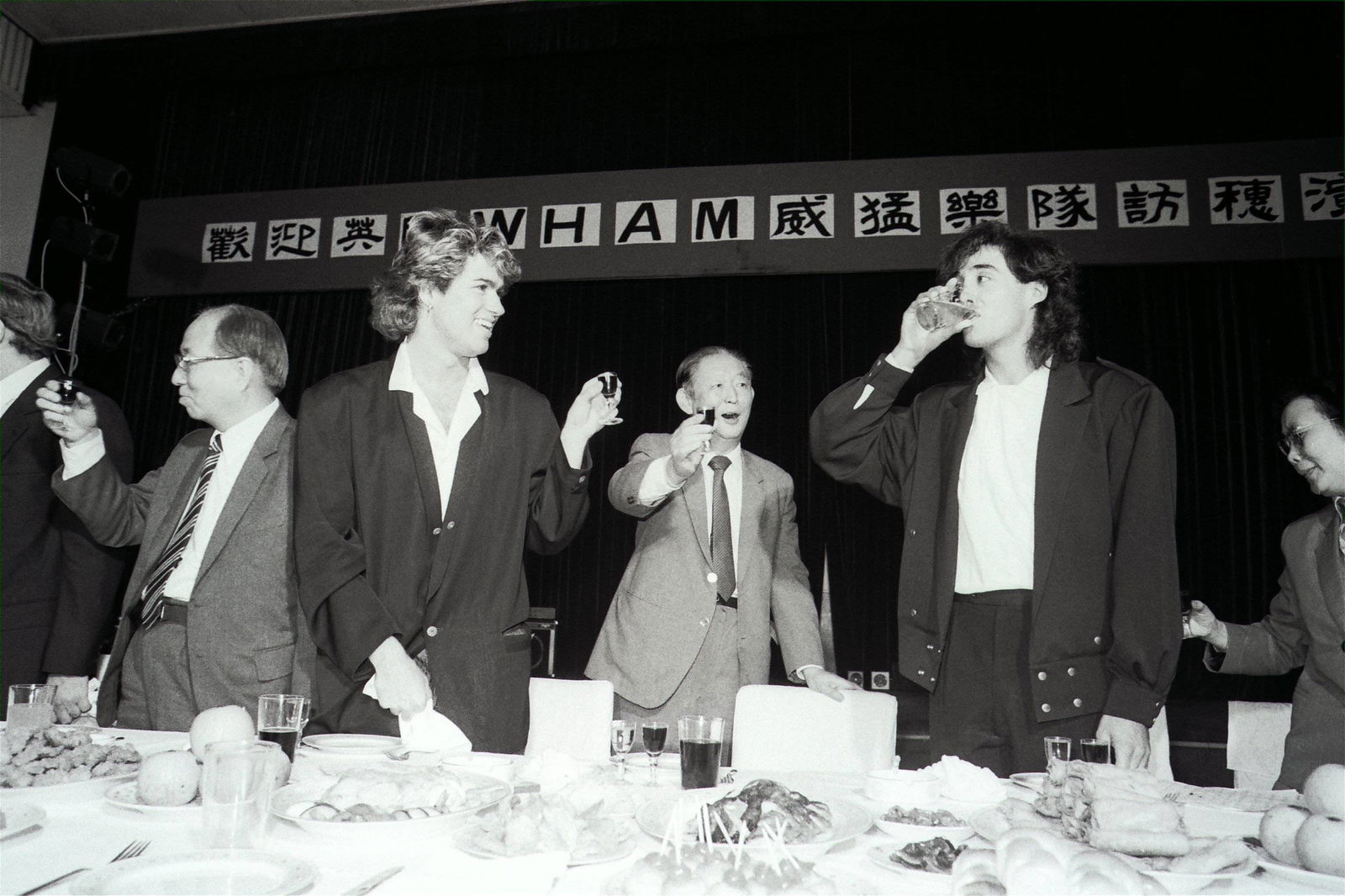 Andrew Ridgeley (rechts) und George Michael (dritter von rechts) von Wham! auf Tournee in China (1985)